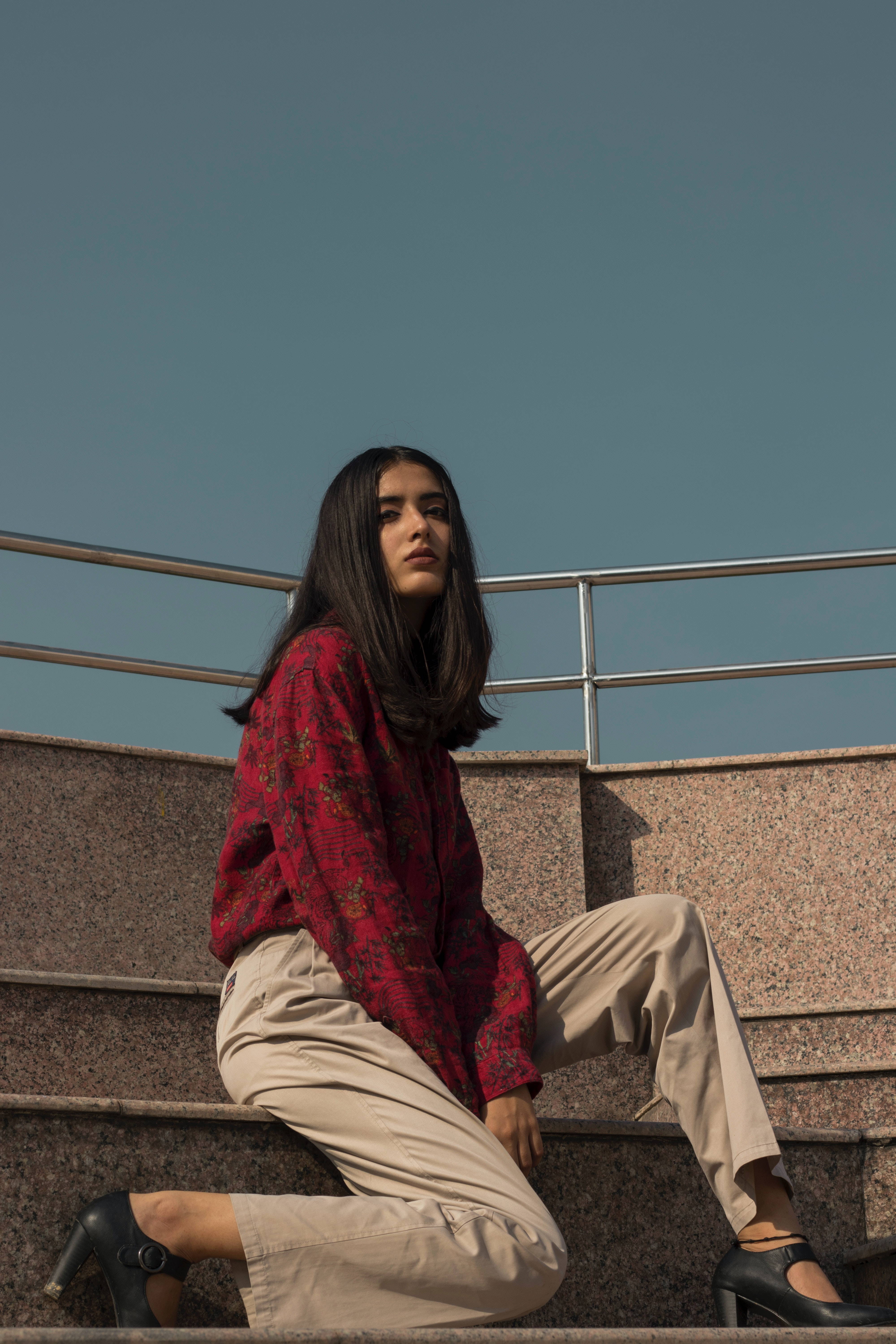 Image of a woman sitting on stairs with a long sleeve red shirt on.